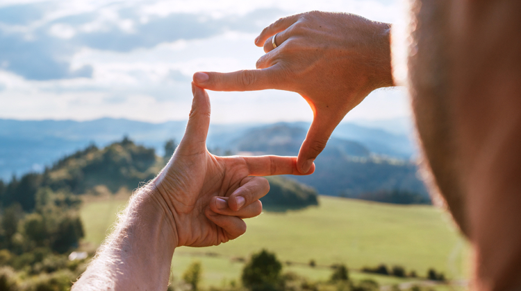 A person looking through a rectangle they are making with their hands.