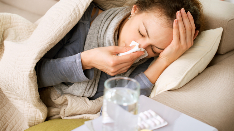 Sick woman in bed with tissue holding her head