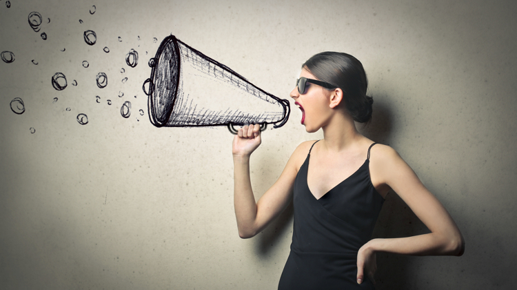 Woman in sunglasses with black dress yelling into megaphone