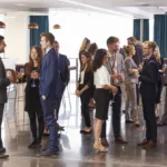 Group of people in business attire standing around and having conversations to network