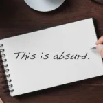 "This is absurd" is written on a notebook that is on a desk; hand copying ads is not an effective method for learning to write copy. Analyzing and rewriting ads is.