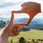 A person looking through a rectangle they are making with their hands.