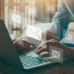 Hands rest on a laptop keyboard while 7 transparent boxes of varying sizes with envelope email icons on them float above the keyboard.