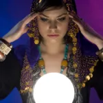 Woman dressed in gypsy attire holds fingers to her temples and stares at a glowing white ball