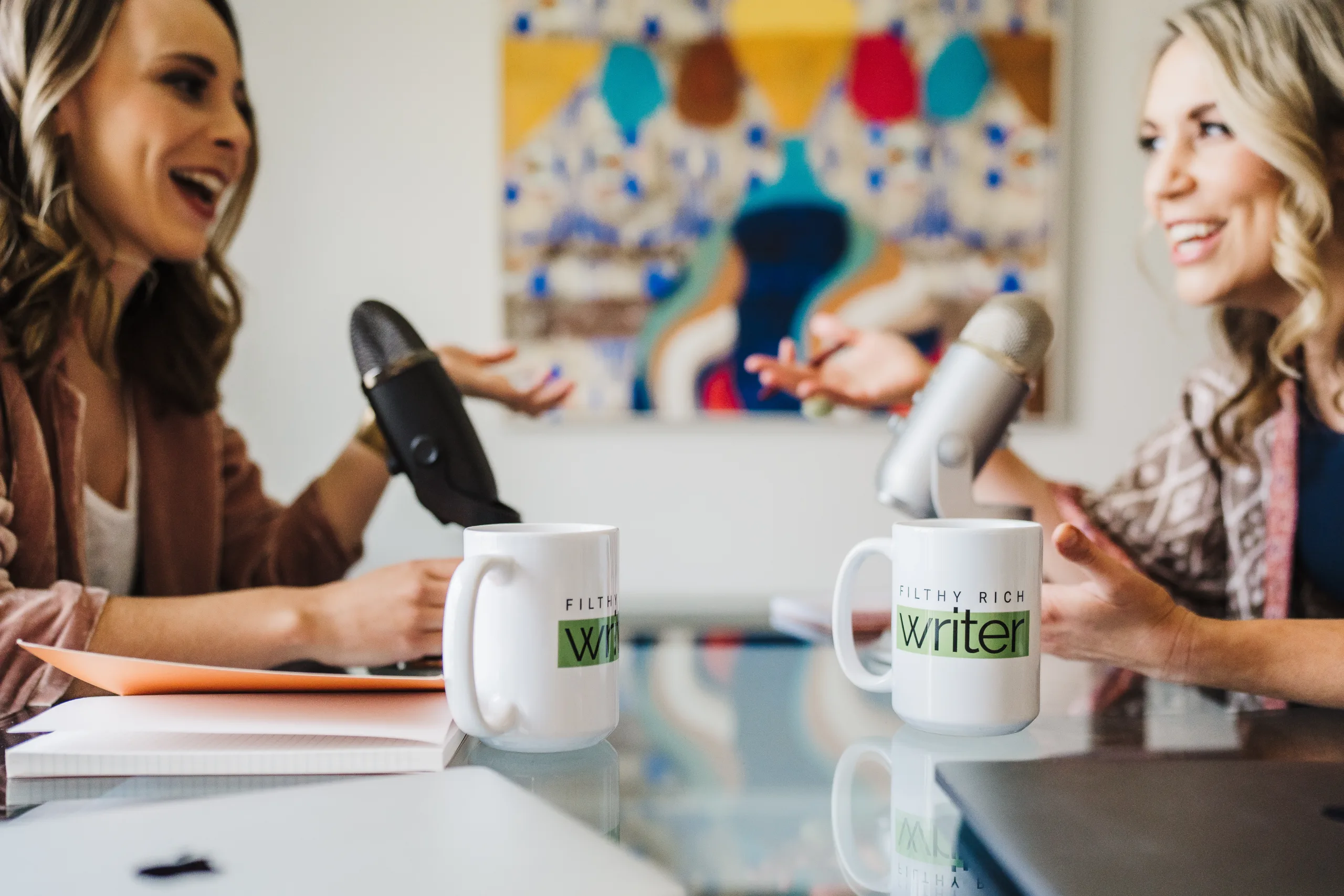 Kate Sitarz and Nicki Krawczyk sitting together with their podcast microphones and notebooks