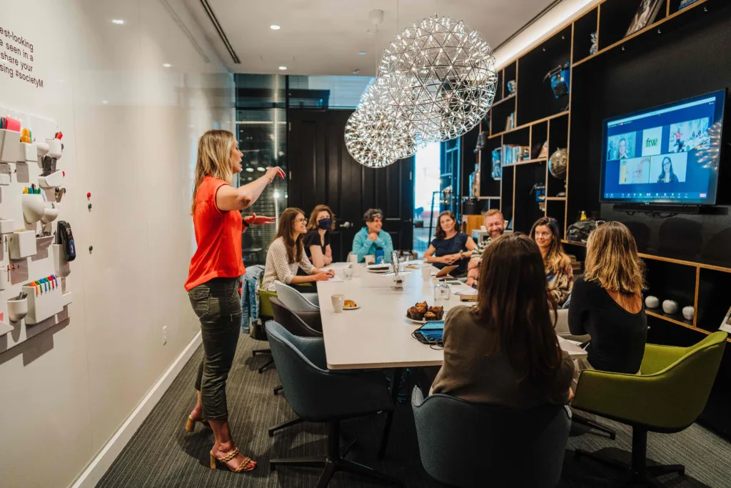 a woman in an orange top conducting a meeting