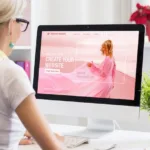 Woman in yellow scarf sits in front of computer screen where she is building her website with drag-and-drop features.