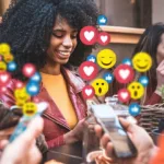 Several people on phones with heart, smile, and thumbs up emoji coming out of mobile phones.