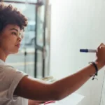 Woman using a marker writes on a whiteboard