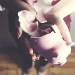 A pair of hands holds a broken ceramic piggy bank.